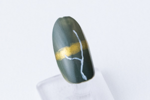 親指と人差し指と中指の爪につまようじの先で、「胡粉」を使って茎となる線を描きます。