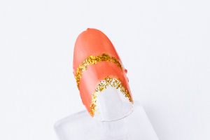 金粉を「スーパーコート」に馴染ませ、爪楊枝で境目を丸く囲み、親指はその上にもカーブを意識した線を引きます。