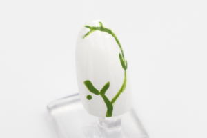 親指、薬指の「胡粉」が乾いたらつまようじで模様を描いていきます。親指は、「鶯緑」で植物のつるを描きます。